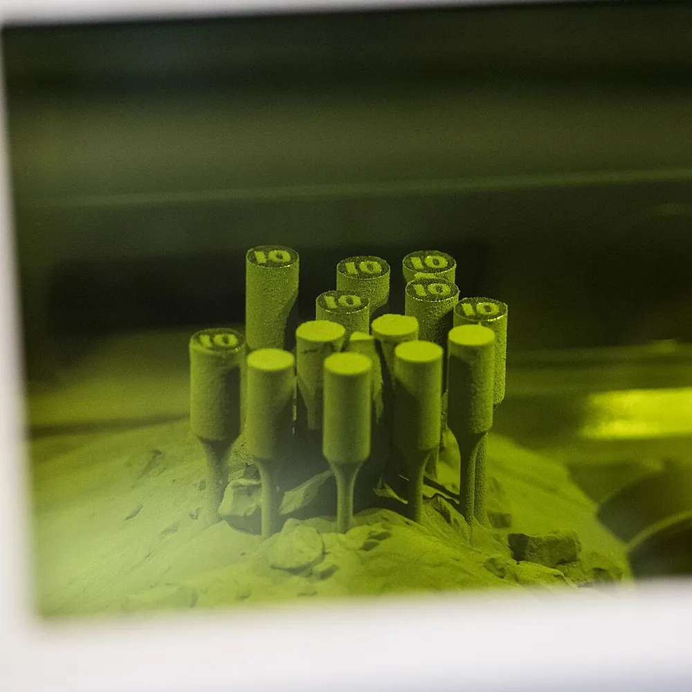 Test pieces standing in metal powder inside a laser powder-bed printer